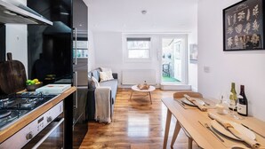 A modern kitchen with a gas stove, a refrigerator, and a dining area with a table set for two.