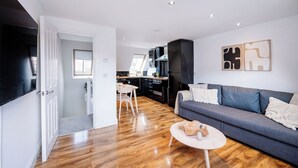 A modern living room with a grey sofa, a coffee table, and a kitchen in the background.