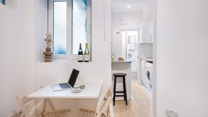 A compact kitchen with a dining area, a washing machine, and a window with bottles.