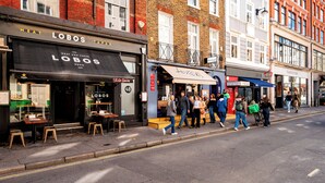 A street with a restaurant named 'LOBOS' and a nearby 'TAPAS' shop. - Soho Studio w/ Kitchen, 1BD/1BA (Greater London)