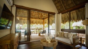 A spacious living area with a wooden floor, a sofa, a coffee table, and a TV mounted on the wall.