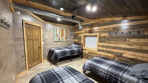A room with two beds, a wooden wall, a painting, and a window with blinds. - Boar's Tusk Lodge (Winner)