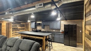A modern kitchen with a central island, built-in appliances, and a rustic wooden interior. - Boar's Tusk Lodge (Winner)