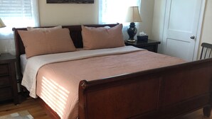 Un dormitorio con cama de madera, una mesita de noche, una lámpara y una puerta.