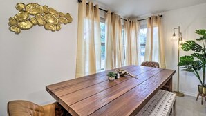 A dining area with a wooden table, beige curtains, and a decorative wall piece.