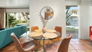 A dining area with a round table, four chairs, a vase with dried flowers, and a round mirror on the wall. - Urban Cowboy Condo – Scottsdale, AZ (Scottsdale)