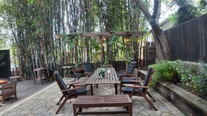 Une terrasse extérieure avec une table et des chaises en bois, entourée de bambous et de verdure.