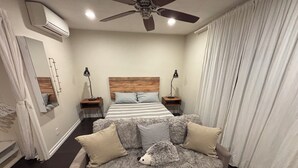 Ein Schlafzimmer mit einem großen Bett, einem kuscheligen Sofa und einem Deckenventilator.