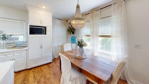 A kitchen with white cabinetry, a wooden dining table, and a chandelier.