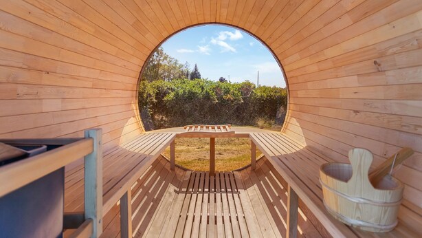 Une structure en bois dotée d’une ouverture circulaire, d’un banc en bois et d’un seau en bois.