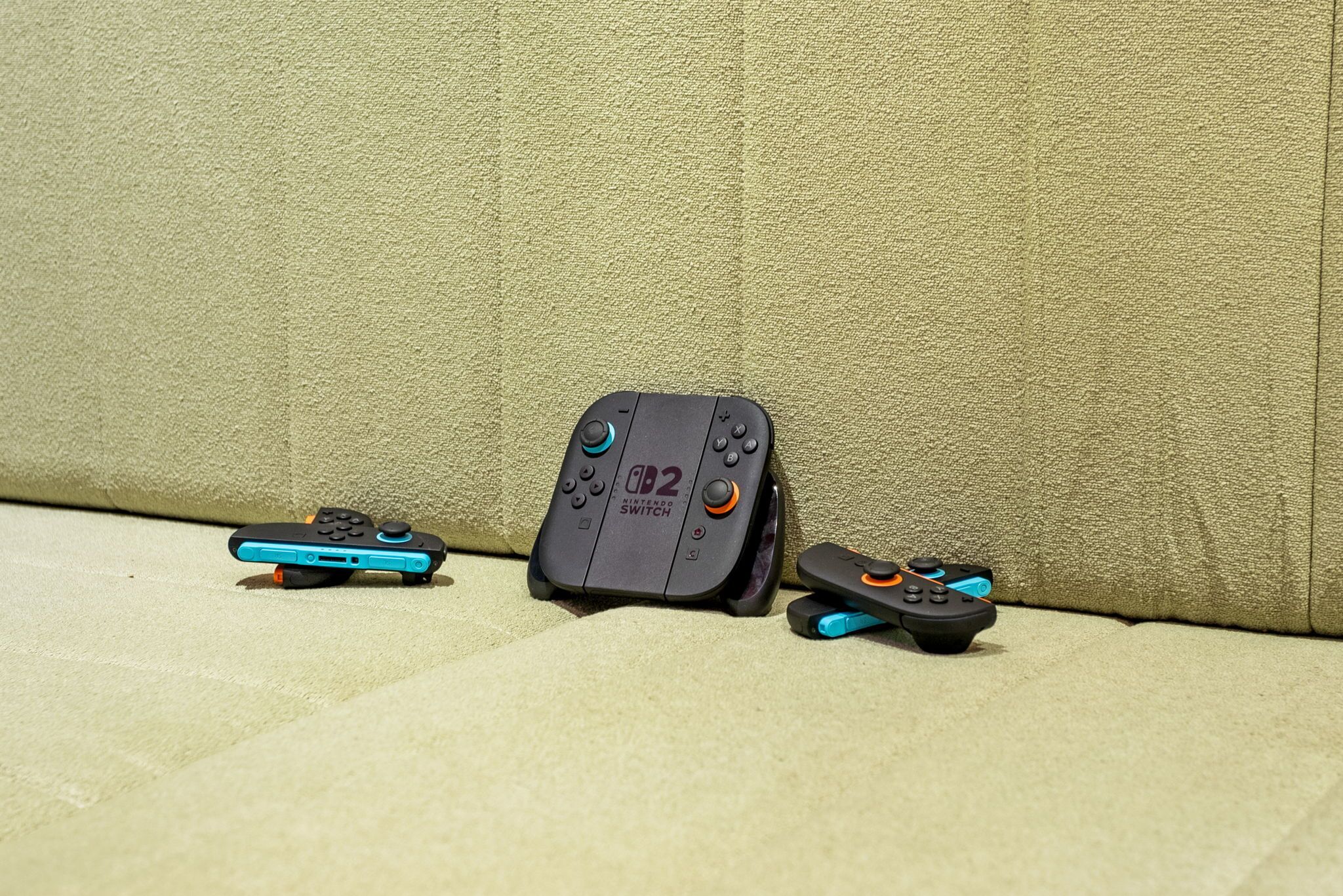A Nintendo Switch console and two Joy-Con controllers on a textured beige couch.