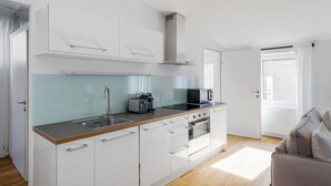 Una cocina moderna con armarios blancos, un lavamanos de acero inoxidable, un microondas y un tostador.