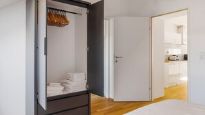 Un dormitorio moderno con un armario, una cama bien hecha y vistas a la cocina.
