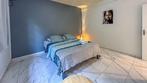 A bedroom with a bed, pillows, a bedside lamp, and a wall art piece. - Wave & Chill Apartment with garden 2 steps from the sea (Sainte-Luce)