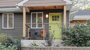 A residential house with a front porch, a green door, and a brick retaining wall. - King + 2 Queen Beds | 3 Smart TV`s | *WALK to LU* (Lynchburg)