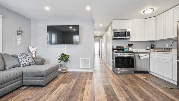A modern kitchen with white cabinets, a stainless steel oven, and a microwave.