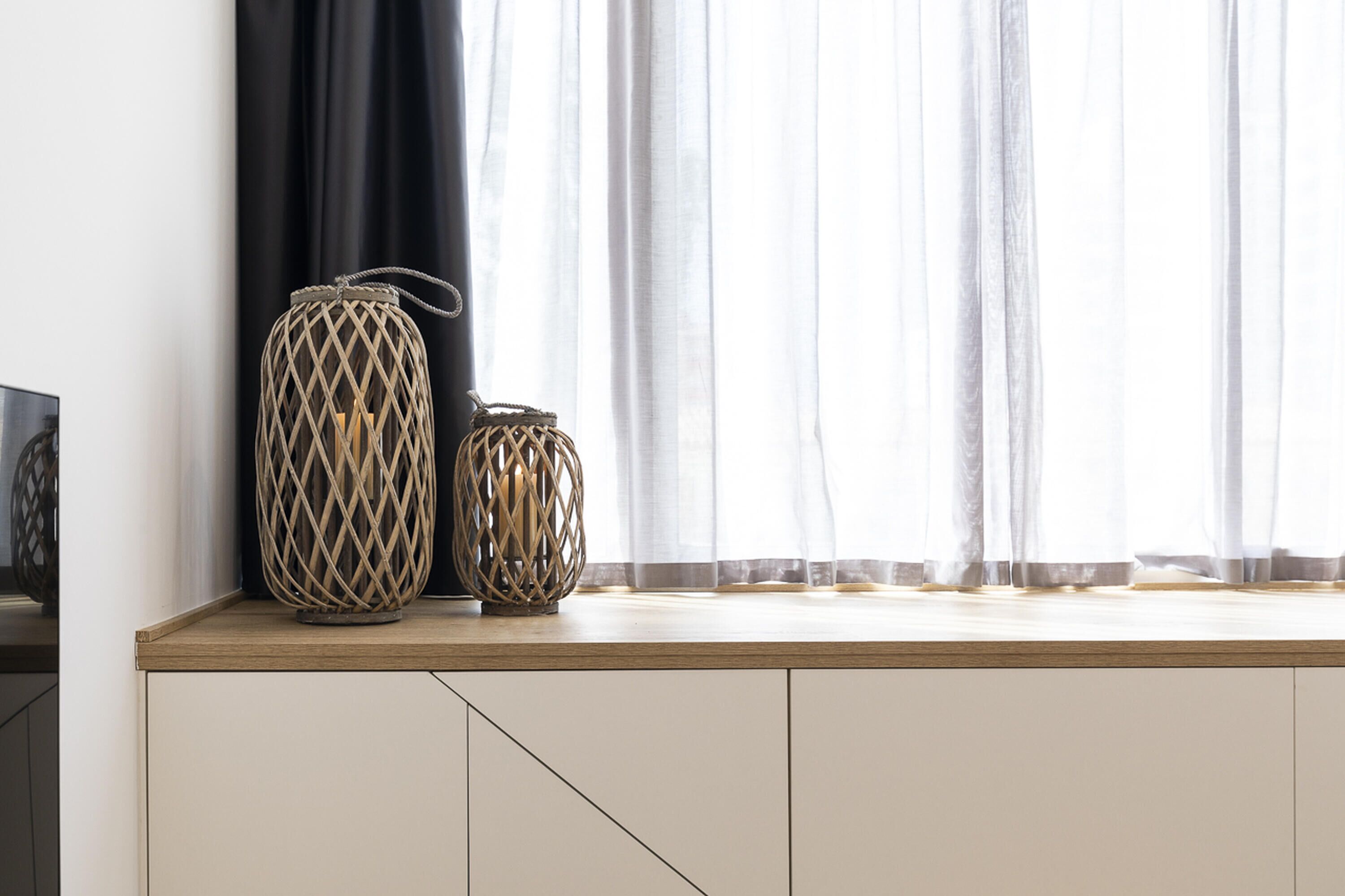 Una ventana con cortinas de encaje blanco y un alféizar de madera.