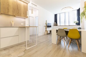 Una cocina moderna con armarios de madera, una zona de comedor con mesa y sillas, y un ventanal con cortinas.