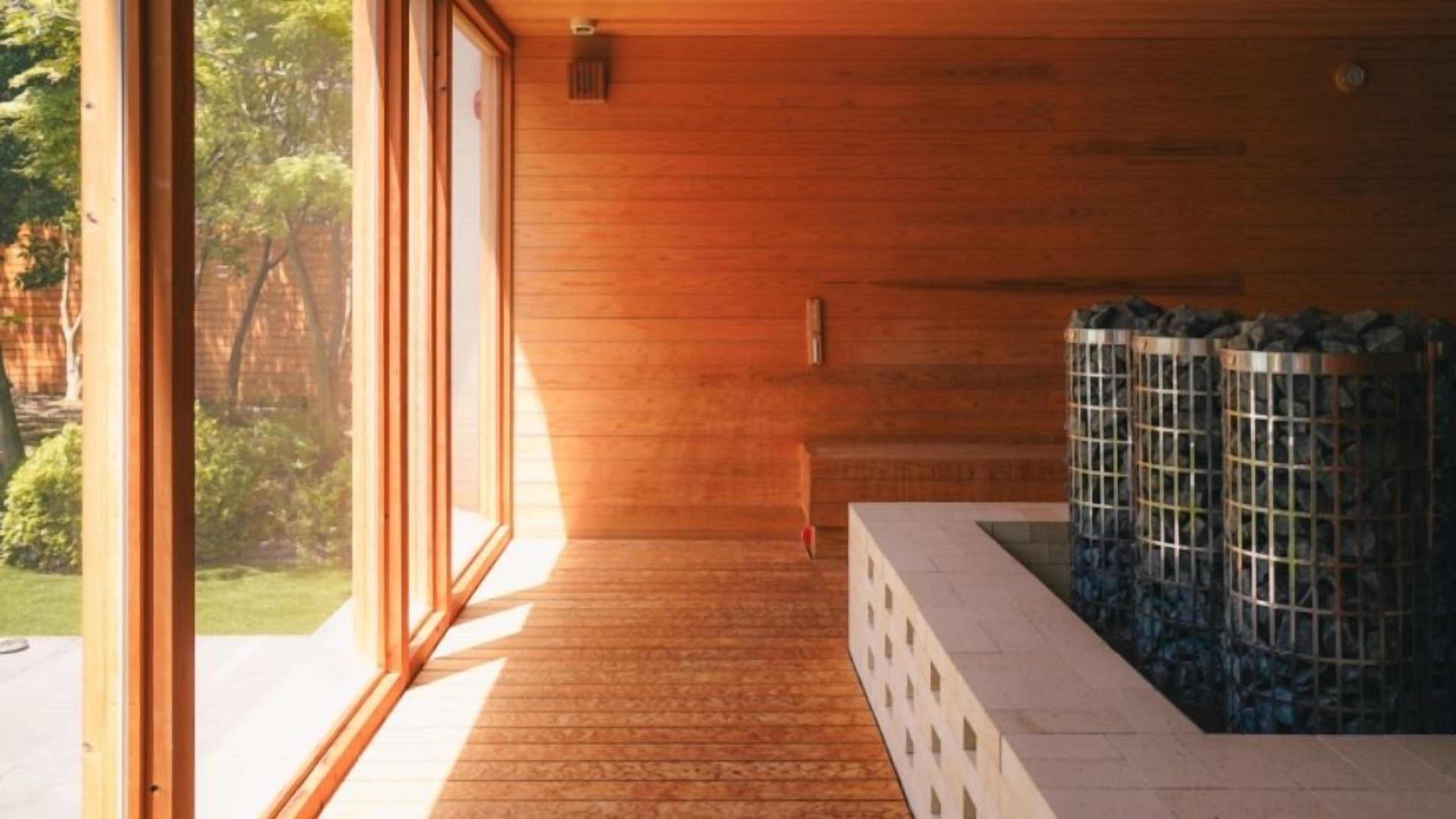 A wooden interior with a sauna, a bench, and a view of the outdoors.