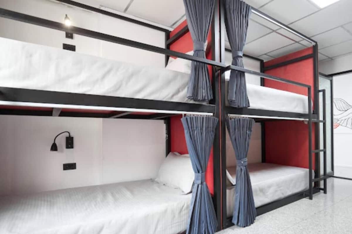 A bunk bed room with a red accent wall, a white mattress, and a curtain.