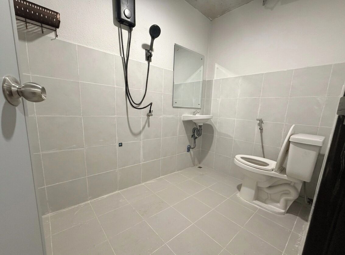 A bathroom with a toilet, sink, mirror, shower, and towel rack.