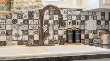 A kitchen with a decorative backsplash, a sink, and two soap dispensers.