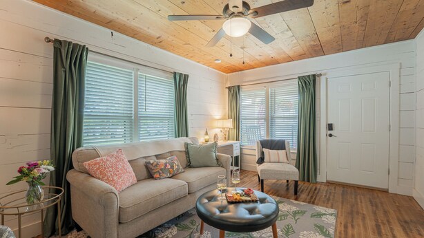 A cozy living room with a sofa, armchair, and ottoman, a ceiling fan, and a wooden floor. - Walk to Eats & Shops • Decatur Courthouse View (Decatur)