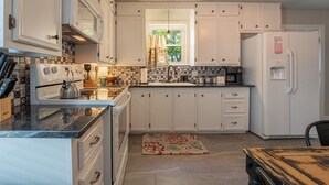 A kitchen with white cabinets, a stove, a refrigerator, and a window with curtains. - Walk to Eats & Shops • Decatur Courthouse View (Decatur)