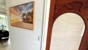 Un couloir avec une porte en bois et un tableau encadré accroché au mur.