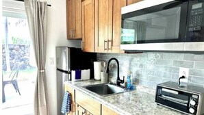 Une cuisine avec des meubles en bois, un réfrigérateur en acier inoxydable, un four à micro-ondes, un évier avec un robinet et un grille-pain.