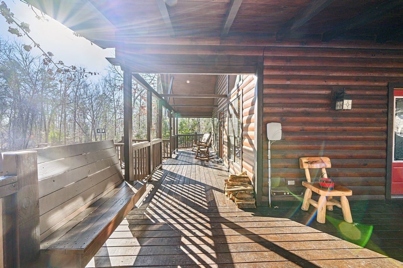 A wooden cabin with a covered porch, a bench, and a chair.