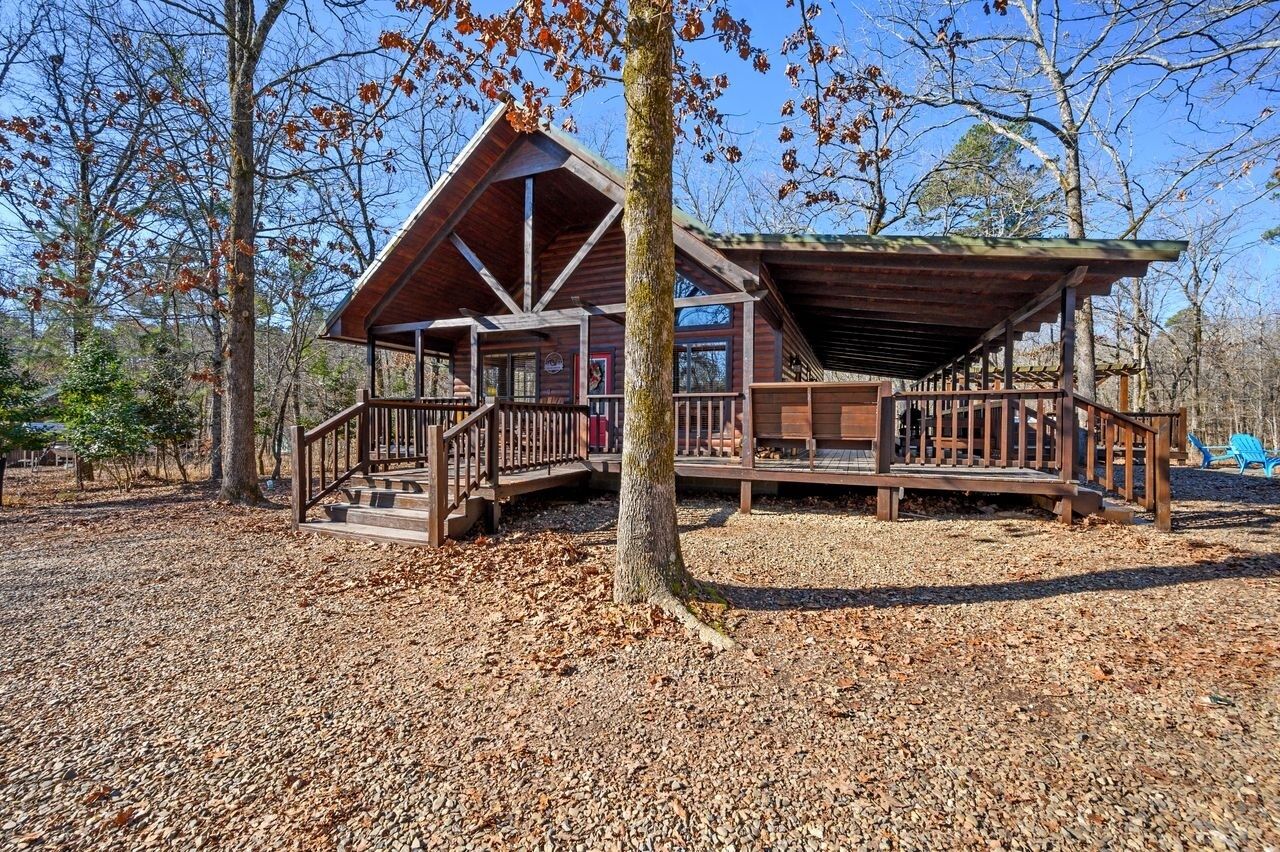 A cabin with a wooden deck, a covered porch, and a staircase leading to the entrance.