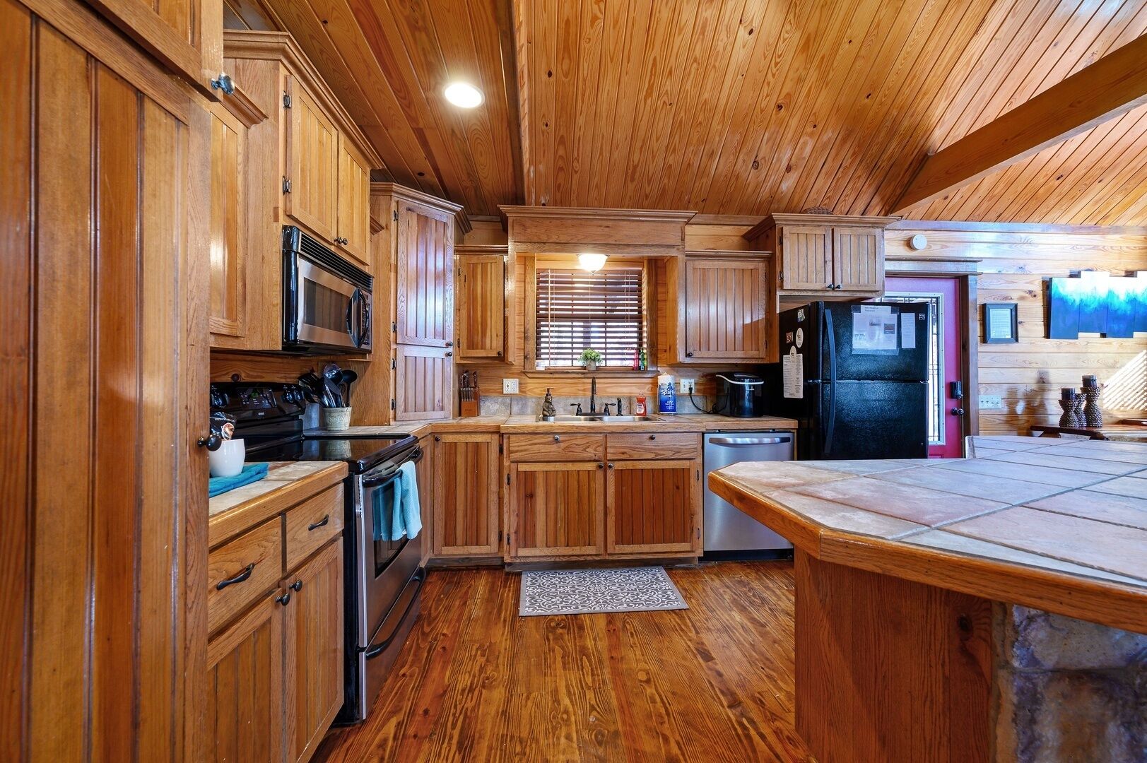 Una cocina amplia con armarios de madera, una isla central y un refrigerador negro.