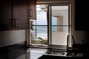 Cozinha com vista para o oceano através de uma porta de correr de vidro.