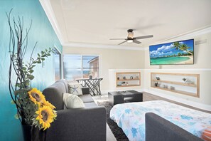 Uma sala de estar moderna com sofá, cama, televisão e ventoinha de teto.