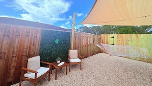 A backyard with a wooden fence, a hammock, and two chairs.