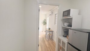 A narrow hallway with wooden flooring leading to a kitchen area.