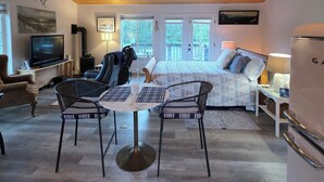 Ein gemütliches Zimmer mit einem Bett, einem Fernseher, einem Deckenventilator und einem Essbereich mit Stühlen und einem Tisch.