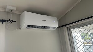 An air conditioning unit mounted on a wall, connected to a power outlet. - Feiloakimisi (Nuku'alofa)
