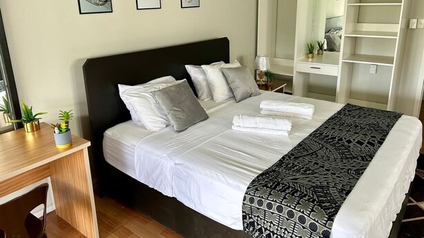 A neatly arranged bedroom with a bed, bedside tables, a desk, and a wardrobe. - Feiloakimisi (Nuku'alofa)