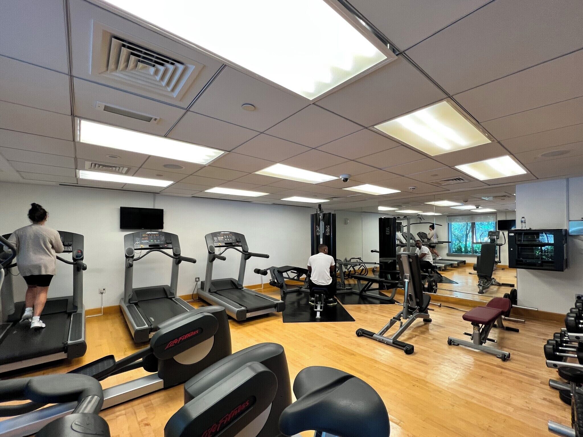 Ett gym med löpband, styrketräningsmaskiner och en vägg full av speglar.