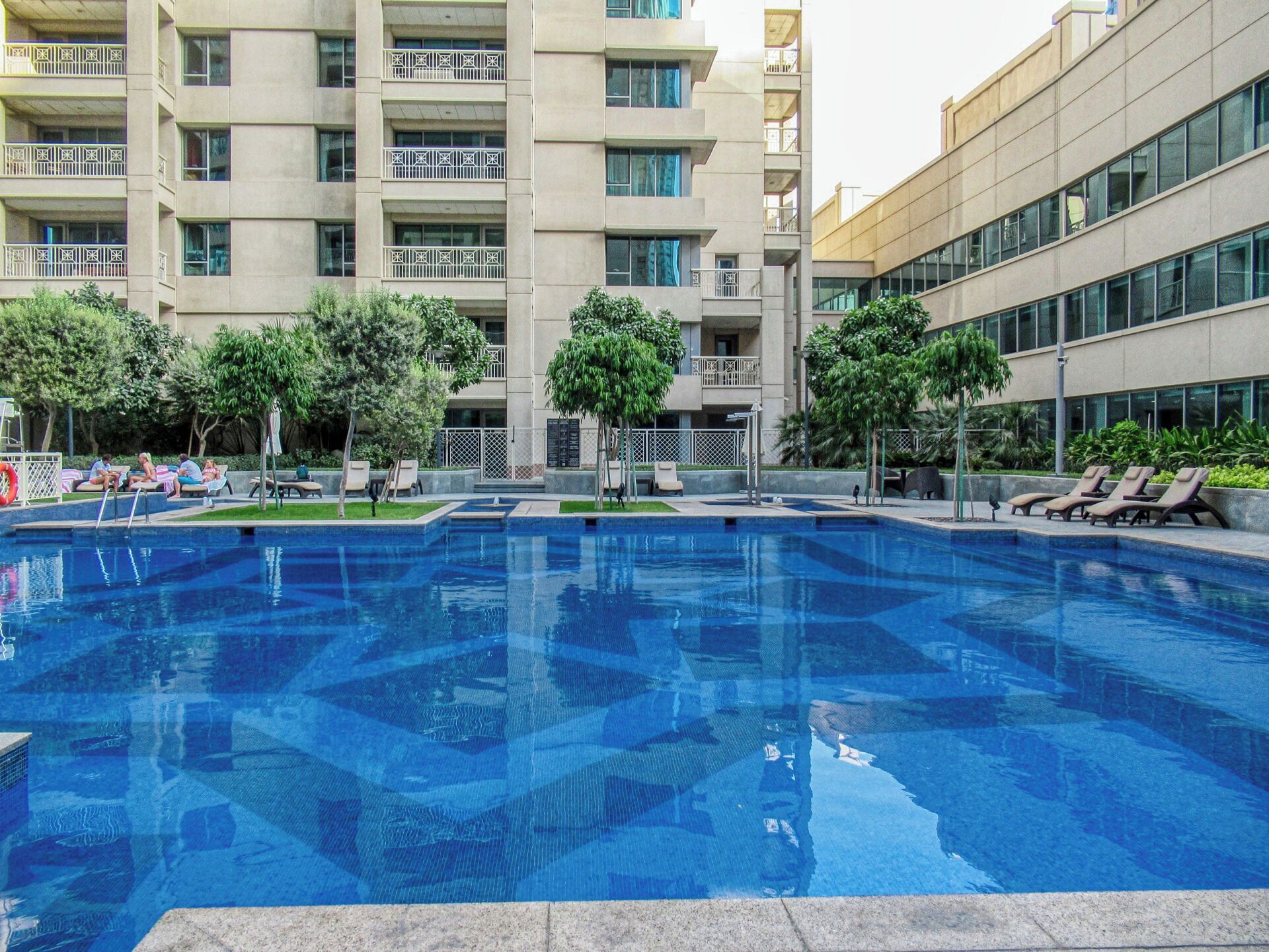 Una piscina al aire libre, sombrillas, sillones reclinables de piscina