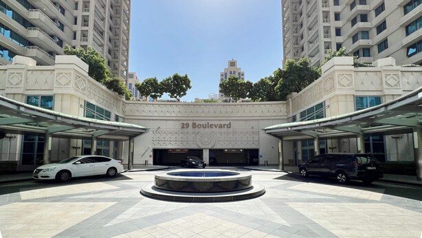 Edificio moderno con patio central, que cuenta con una fuente, rodeado de edificios residenciales altos.