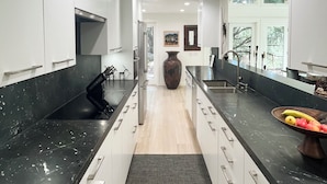 A modern kitchen with white cabinets, black countertops, and a central island. - Beautiful Riviera Guest Suite in Private Forest, Conveniently Located Retreat (Santa Barbara)