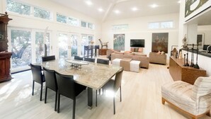 A spacious living area with a dining table, sofas, and a TV. - Beautiful Riviera Guest Suite in Private Forest, Conveniently Located Retreat (Santa Barbara)