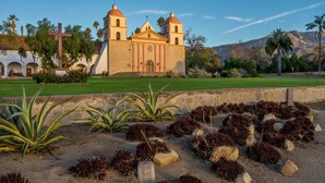 Une église historique, reconnaissable à sa croix imposante, entourée d’un jardin aménagé où l’on trouve diverses plantes et rochers.