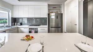 Eine moderne Küche mit weißen Schränken, einem Edelstahl-Kühlschrank und einem Essbereich mit einem weißen Tisch, gedeckt für zwei Personen.