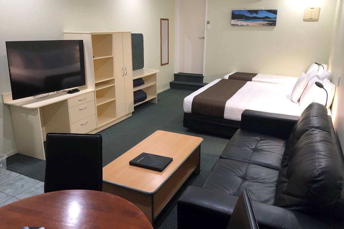 A hotel room with a TV, a desk, a sofa, a bed, and a wardrobe.