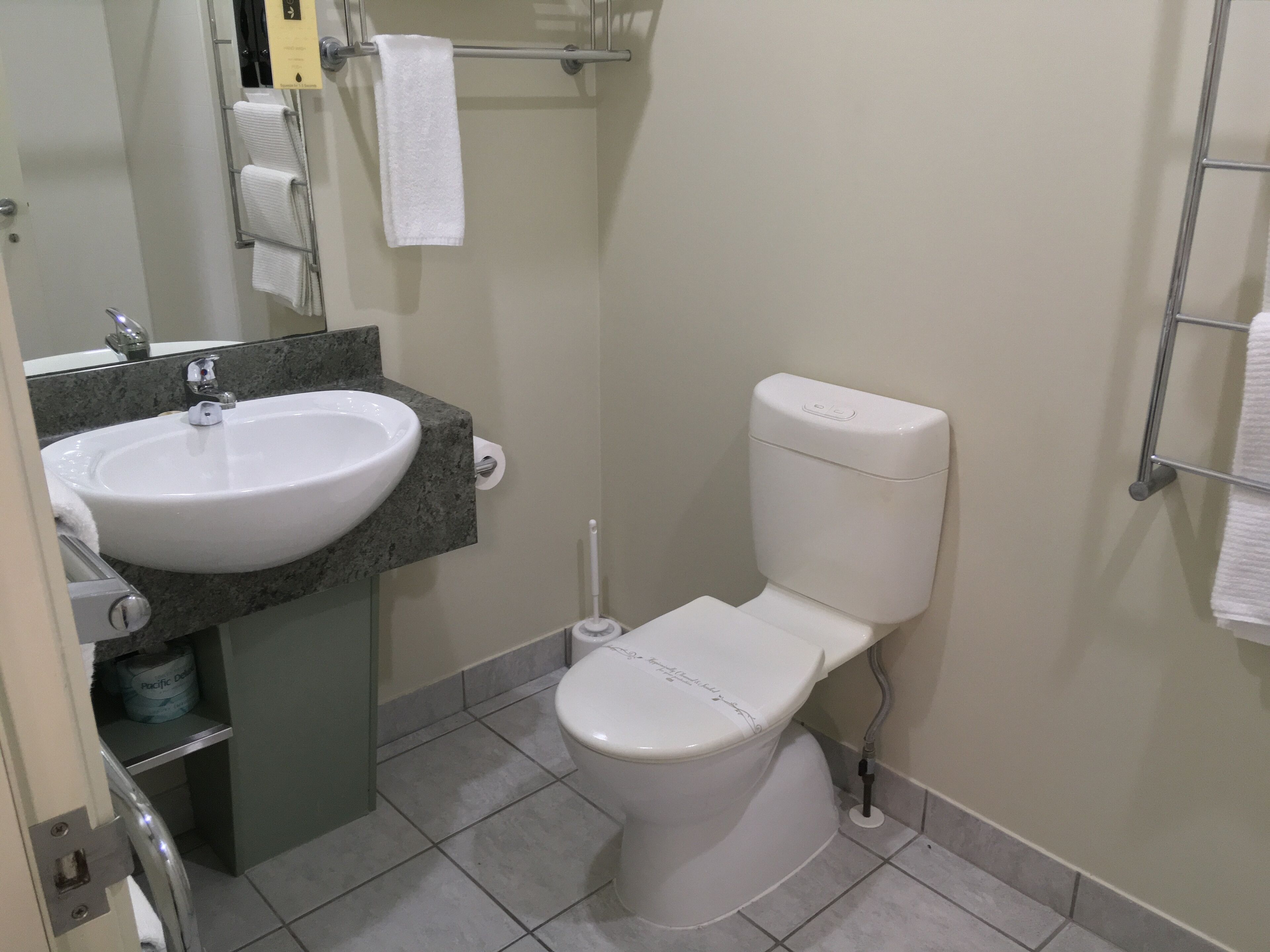 A bathroom with a white sink, toilet, and a towel rack.