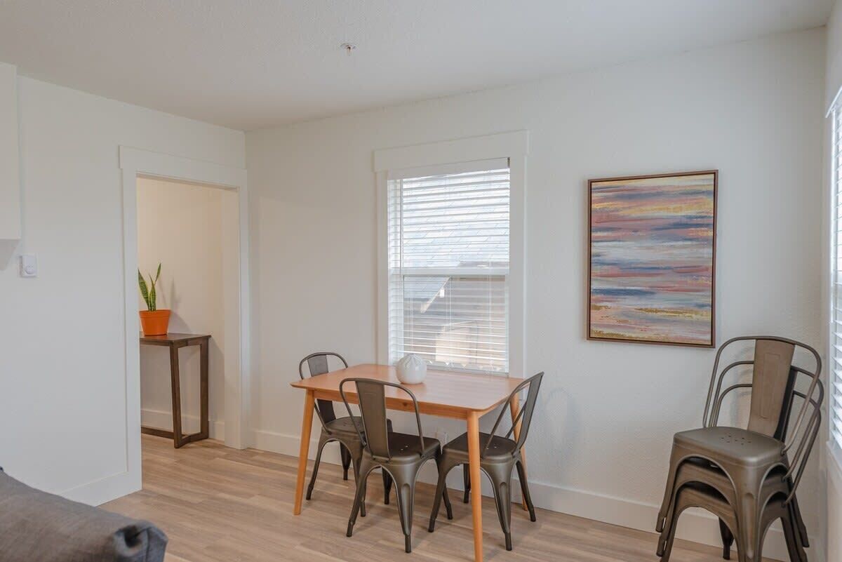 Un coin repas avec une table en bois et des chaises en métal, une plante en pot et un tableau accroché au mur.